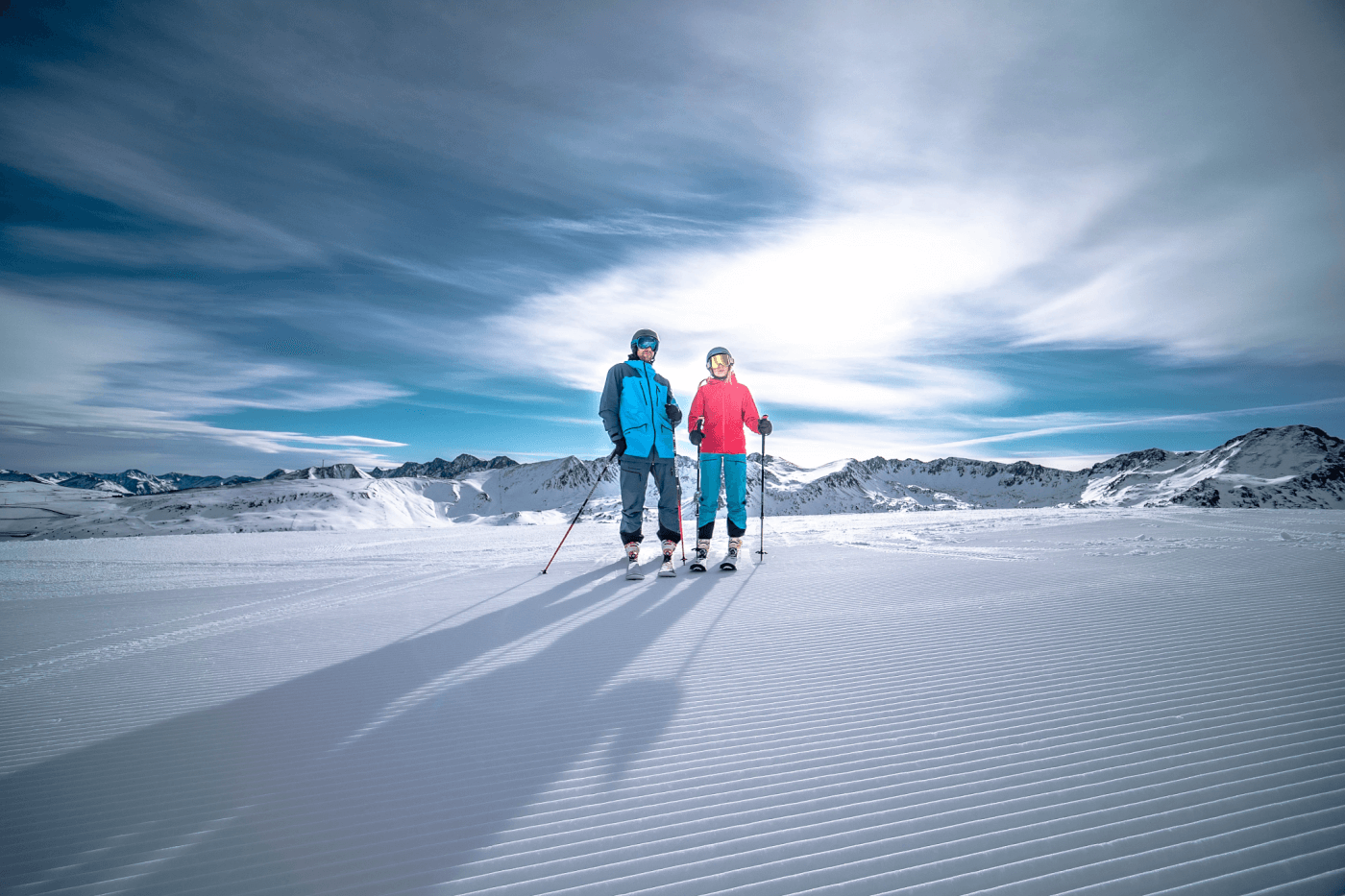 Two people skiing with shadows showing on the snow.